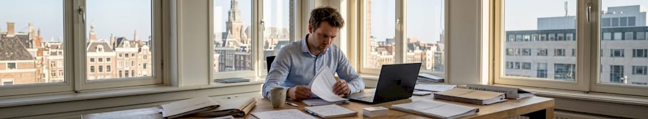 Een ondernemer buigt zich over zijn verzekeringspapieren op kantoor.