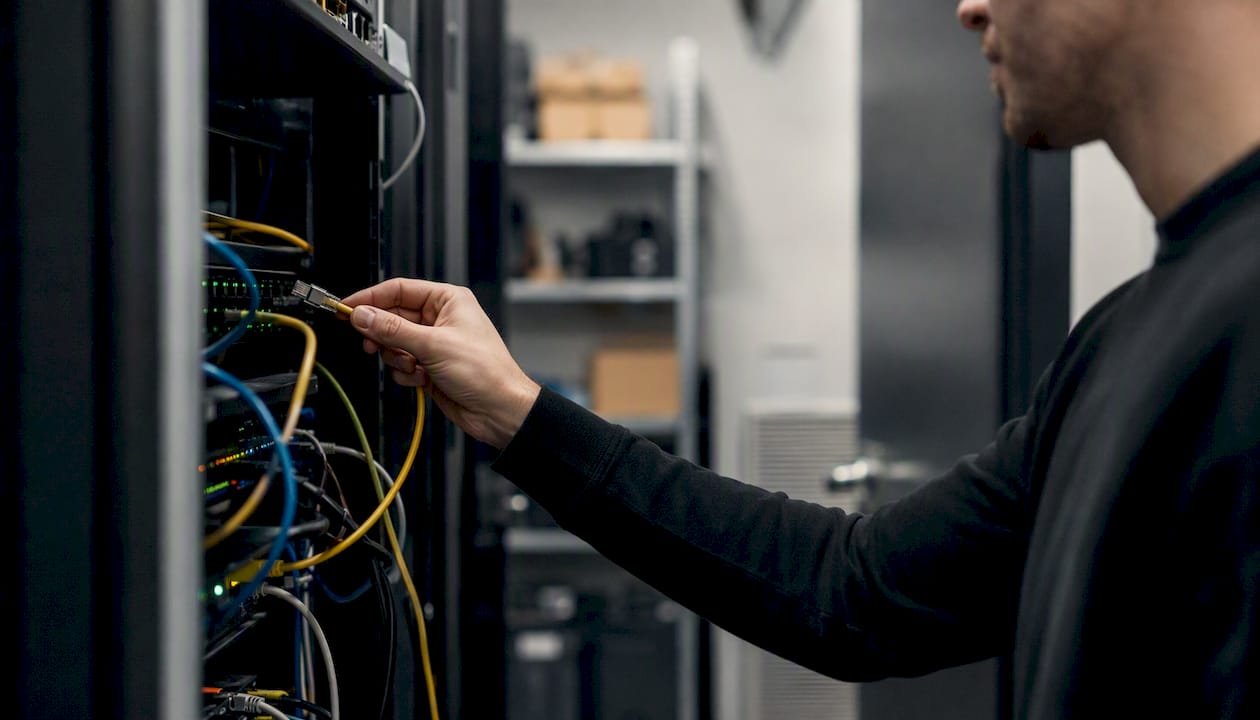 Een technicus is bezig om serverapparatuur los te koppelen.