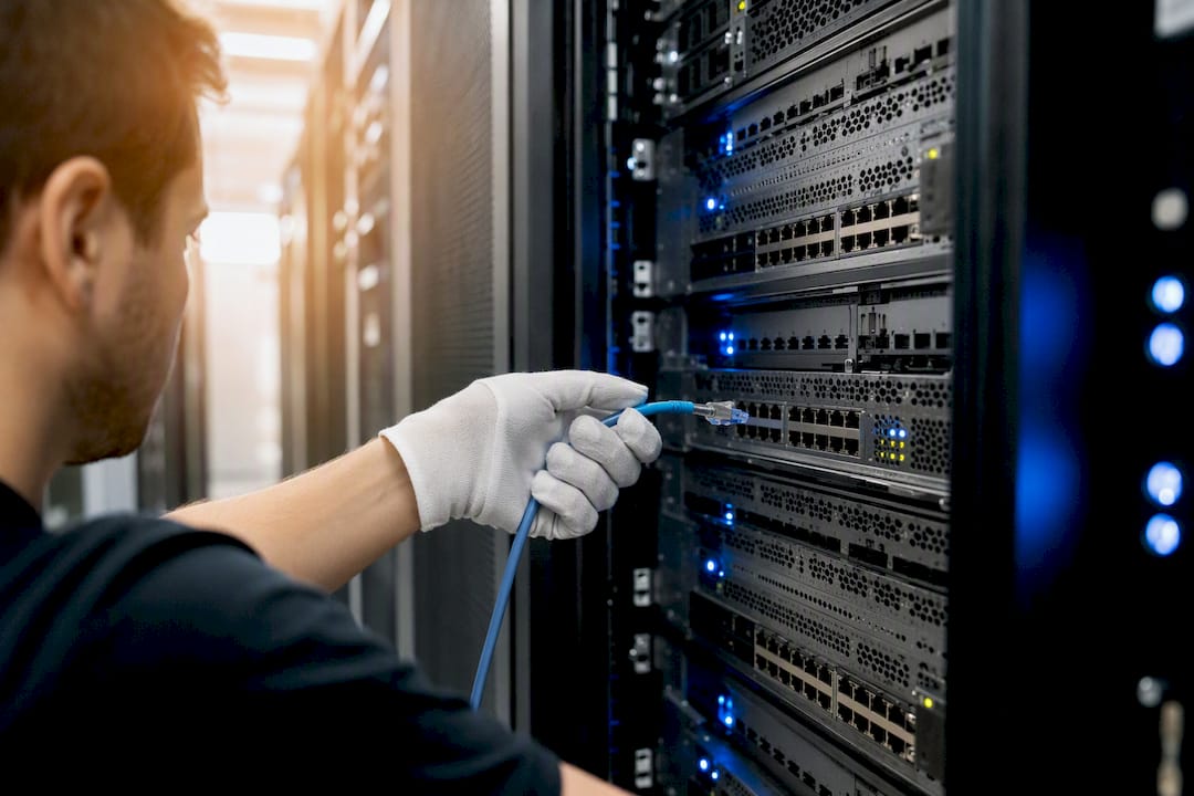 Een technicus haalt een netwerkkabel uit een serverkast.