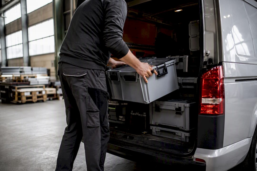 Handen die gereedschapskisten in een bestelwagen laden